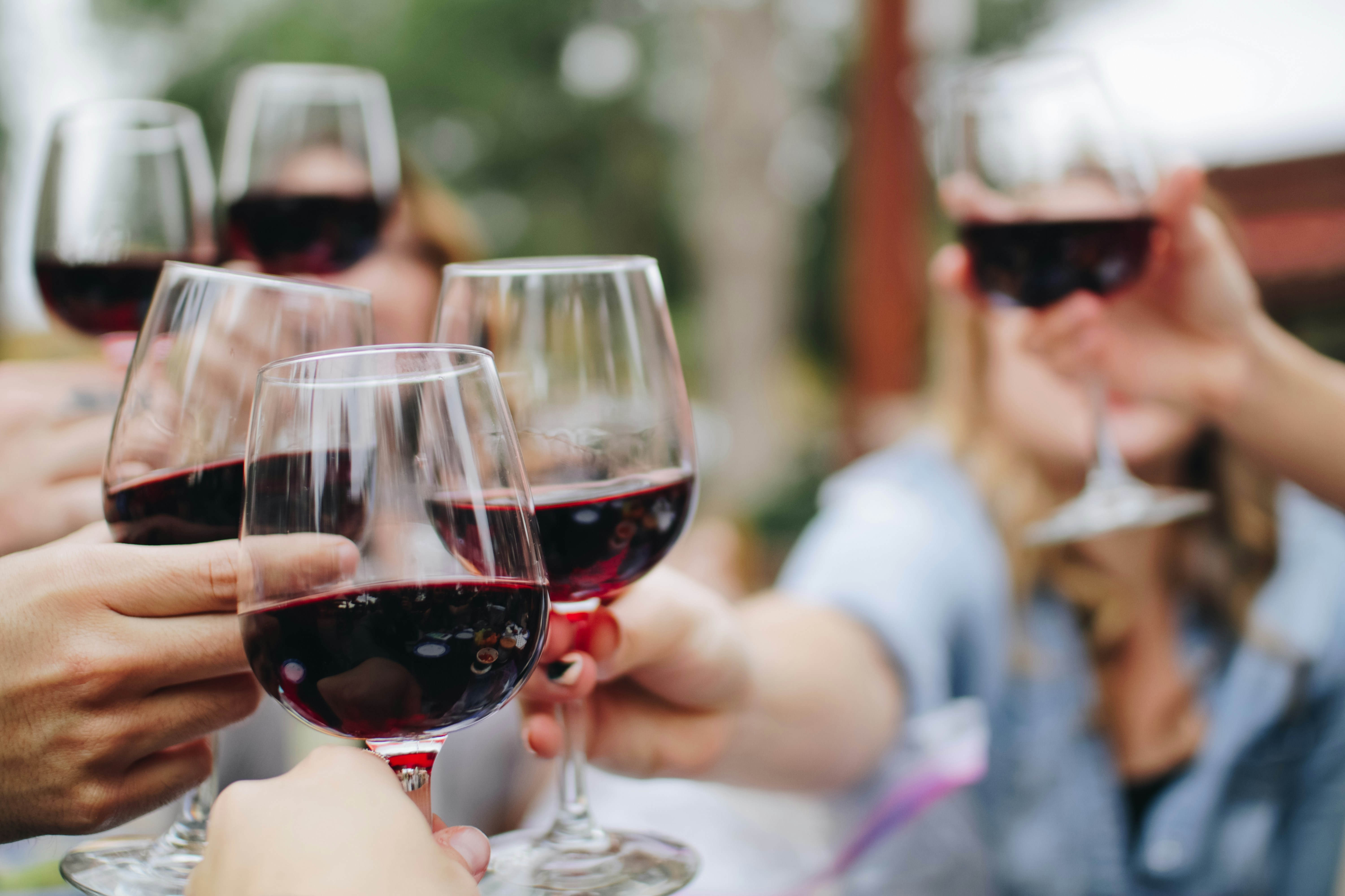 Groep mensen die buiten proosten met glazen rode wijn
