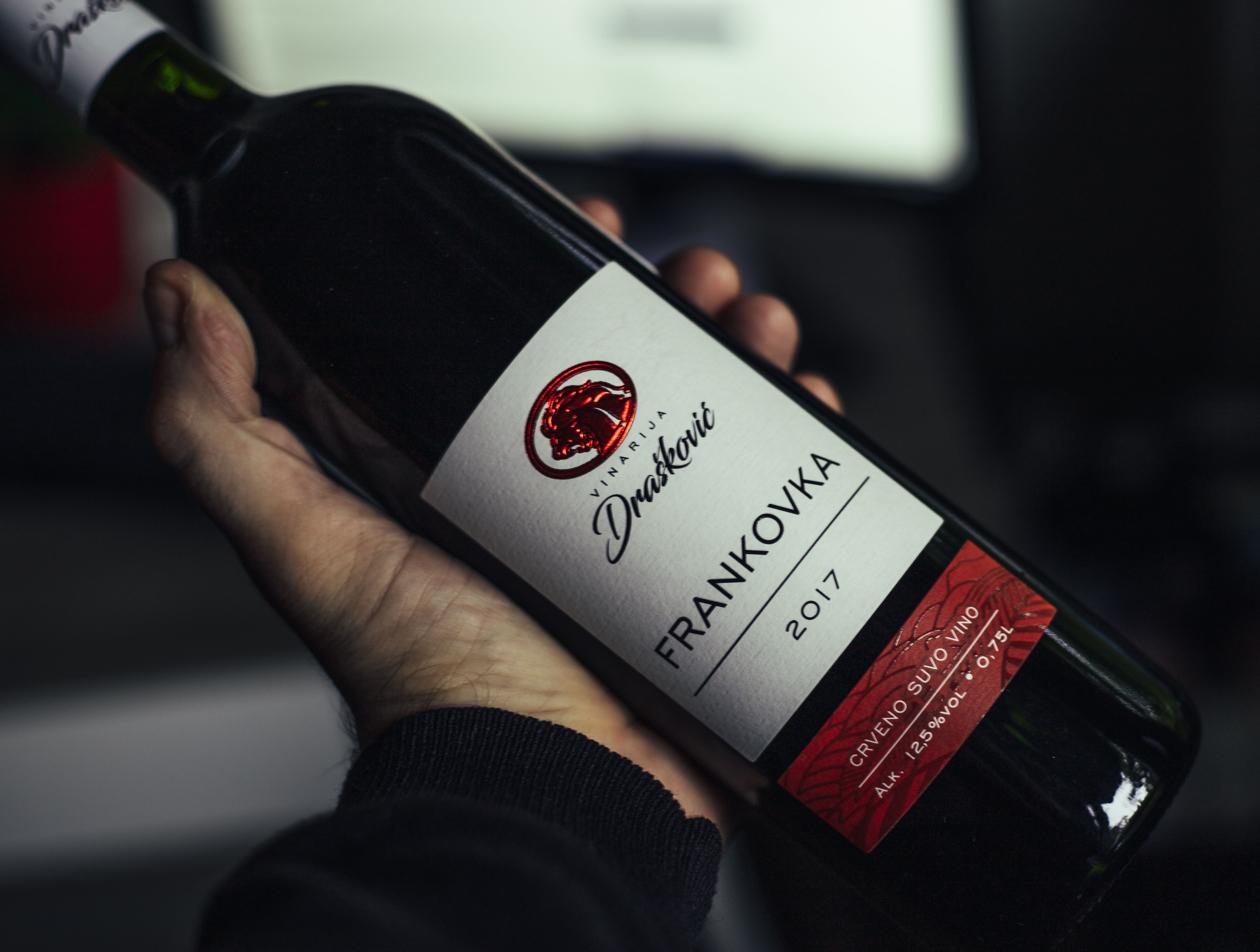 Hand die een fles rode wijn vasthoudt, etiket goed zichtbaar